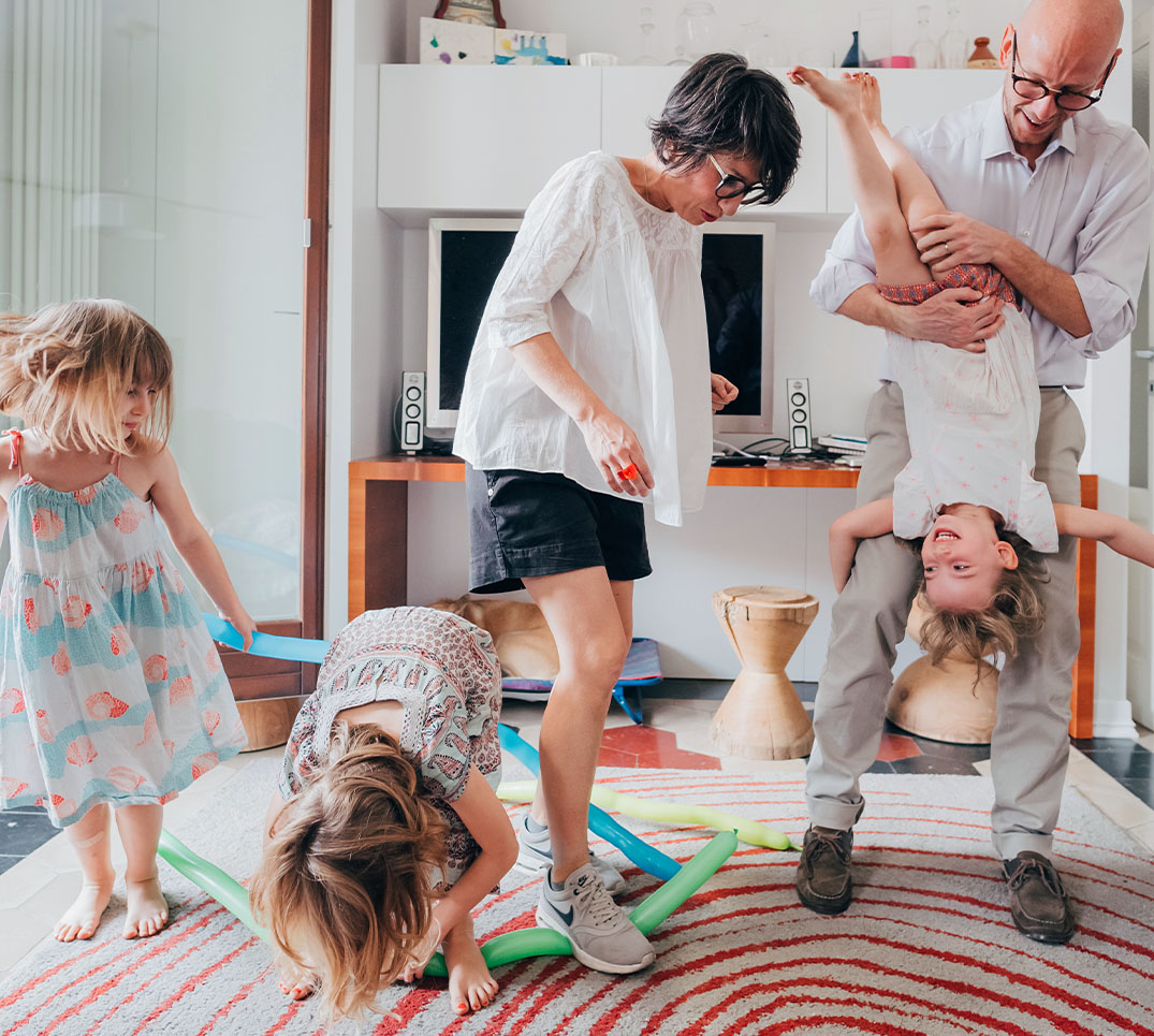 Famille active en train de jouer à la maison Les parents jouent avec entrain avec leurs enfants, une famille active et en bonne santé