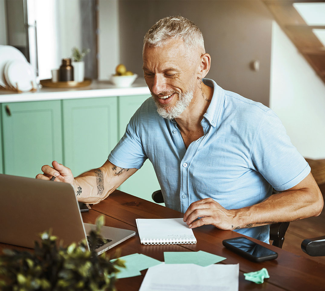 Comparer les caisses d'assurance maladie depuis chez soi – PRO VITA AG Un homme compare les primes d'assurance maladie sur son ordinateur portable, chez lui – conseil indépendant par PRO VITA AG