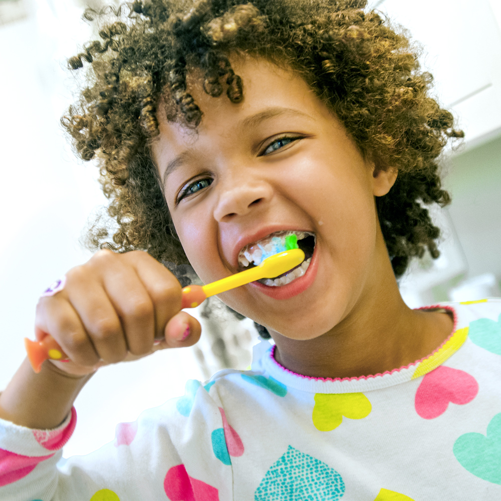 Un enfant se brosse les dents avec une brosse à dents. L’accent est mis sur l’hygiène dentaire quotidienne à domicile.