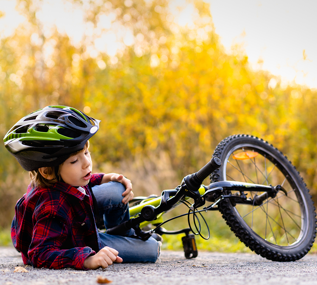 Ein Kind sitzt nach einem Fahrradsturz am Boden. Solche Unfälle gehören zu den häufigsten Auslösern für Zahnverletzungen bei Kindern in der Schweiz.