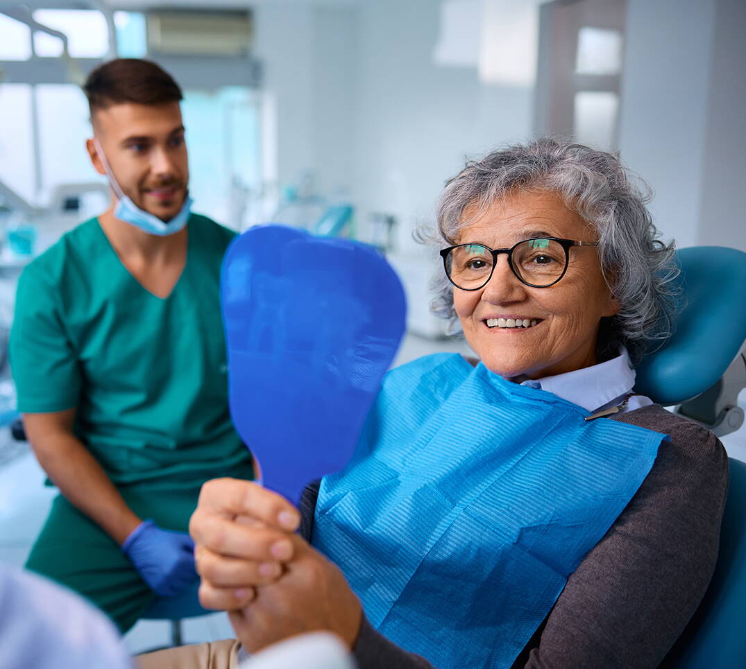 Zahnbehandlung im Erwachsenenalter: Nach einer Behandlung überprüft die Patientin das Ergebnis. Veränderungen am Gebiss und grössere Eingriffe gehören zu den häufigsten Kostenfaktoren bei Zahnversicherungen.