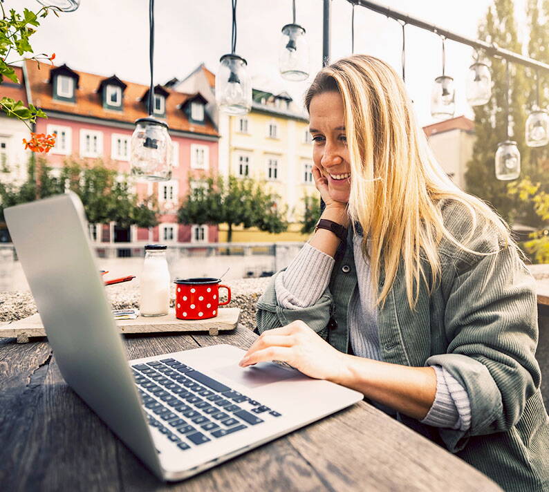 Frau vergleicht Krankenkassenoptionen entspannt am Laptop im Freien – unabhängige Beratung durch PRO VITA AG