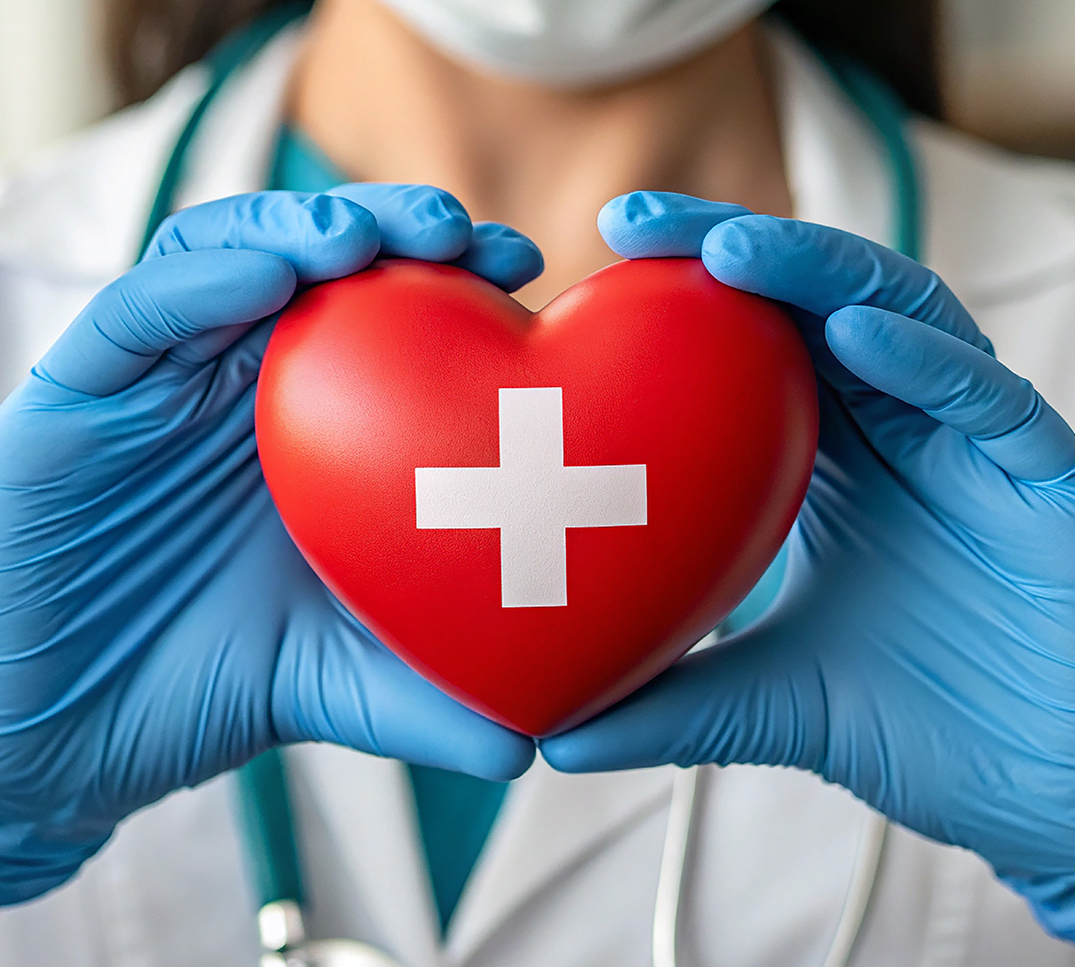 Una persona in abbigliamento medico tiene tra le mani un cuore rosso con una croce svizzera bianca. L’immagine simboleggia l’assistenza sanitaria in Svizzera.