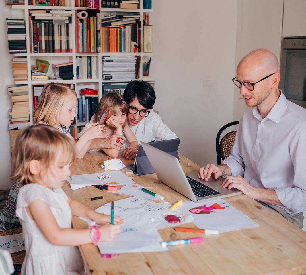 Le père se renseigne sur son ordinateur portable sur la franchise adaptée, pendant que les enfants dessinent à table